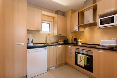 a kitchen with white appliances and wooden cabinets at Quinta Barracuda Albufeira in Albufeira