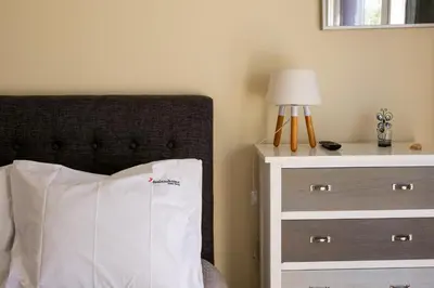 a bed with a white pillow next to a dresser at FLH Falésia Flat with Pool in Vilamoura