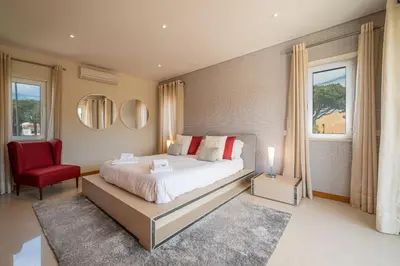 a bedroom with a large bed and a red chair at VILLA SIBLING 2 in Vilamoura