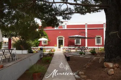 a red building with a table and chairs in front of it at Guest House Almeixar in Almancil