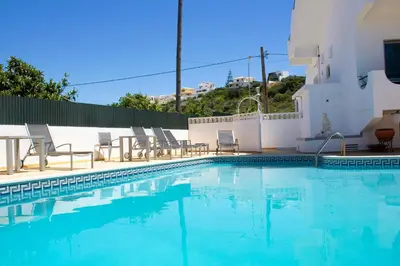 a swimming pool with chairs and a building at AAA Apartments in Albufeira