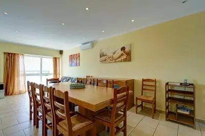 a dining room with a wooden table and chairs at CASA MALINDI in Albufeira