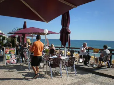 a group of people sitting at tables near the ocean at CASA MALINDI in Albufeira