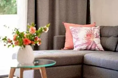 a living room with a couch and a table with a vase of flowers at Vilamoura new style apt piscina wifi in Vilamoura