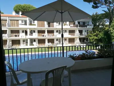 a table with an umbrella next to a swimming pool at Vilamoura T1 com piscina - Mouramar I in Vilamoura