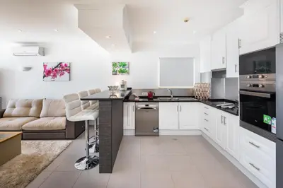 a kitchen with white cabinets and a large island at Apartamentos Mónaco by Garvetur in Albufeira