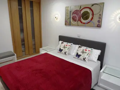 a bedroom with a bed with a red bedspread at CASA OKSANA in Albufeira