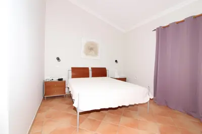 a bedroom with a white bed and purple curtains at Villa Martina - São Rafael - Albufeira in Albufeira