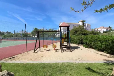a playground with a swing set on a tennis court at Villa Martina - São Rafael - Albufeira in Albufeira