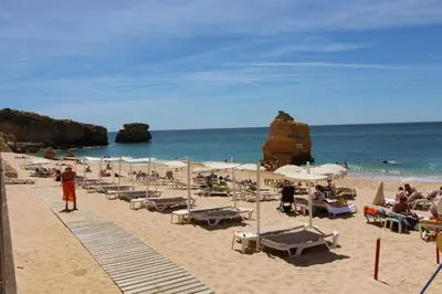 a beach with chairs and umbrellas and the ocean at Villa Martina - São Rafael - Albufeira in Albufeira