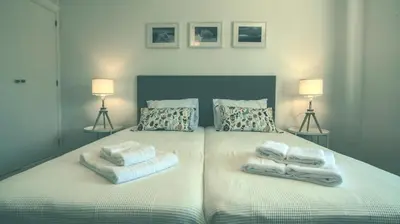 a bedroom with two towels on a bed with two lamps at Pine House - Faro Airport, Beach and City Center in Faro