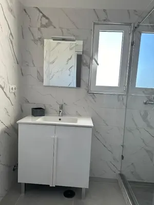 a white bathroom with a sink and a mirror at Duplex Marina de Vilamoura in Vilamoura