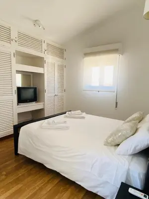 a bedroom with a white bed and a television at Duplex Marina de Vilamoura in Vilamoura