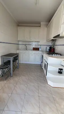 a kitchen with white cabinets and a table in it at Quarteira Beach in Quarteira