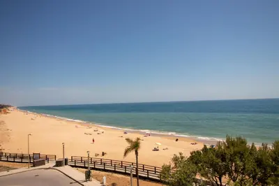 a beach with people on the sand and the ocean at Quarteira Beach in Quarteira