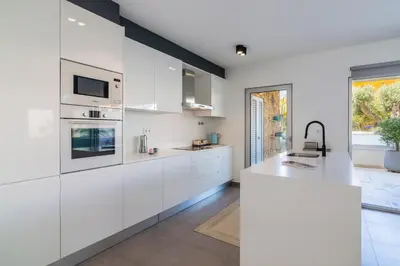 a white kitchen with white cabinets and a large window at Garden Design in Albufeira