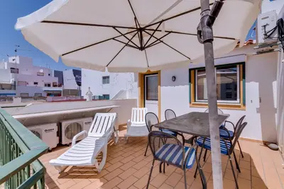 a patio with a table and chairs and an umbrella at Casa Luz - Quarteira in Quarteira