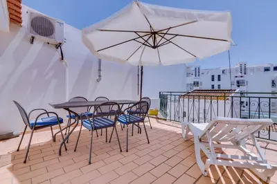 a patio with a table and chairs and an umbrella at Casa Luz - Quarteira in Quarteira