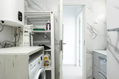 a white kitchen with a washer and dryer at Moura Suites III - Relaxing view - Vilamoura HD Properties in Vilamoura