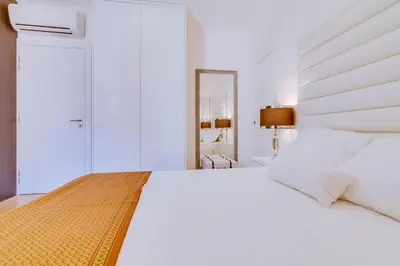 a white bedroom with a large white bed and a mirror at Gold II - Luxurious apartment - Vilamoura in Vilamoura