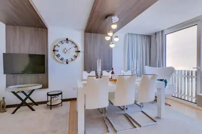 a dining room with a table and white chairs and a clock at Gold II - Luxurious apartment - Vilamoura in Vilamoura
