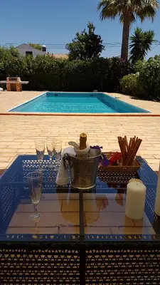 a table with wine glasses and candles on a table with a pool at Villa Navita in Loulé