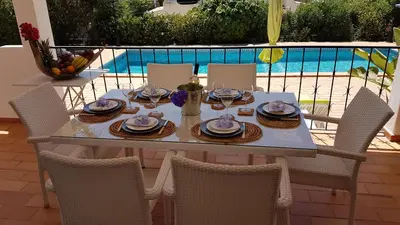 a table and chairs on a patio with a pool at Villa Navita in Loulé