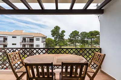 a wooden table and chairs on a balcony at CAROB APARTMENT - BY MAYORAL (FALÉSIA BEACH) in Olhos de Água
