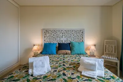 a bedroom with a large bed with blue pillows at CAROB APARTMENT - BY MAYORAL (FALÉSIA BEACH) in Olhos de Água
