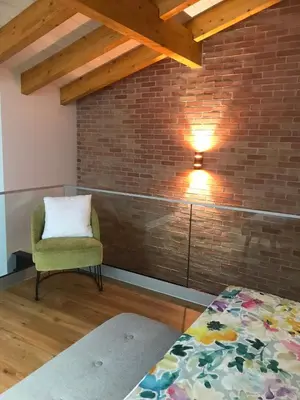 a room with a bed and a chair and a brick wall at Porta 20 in Loulé