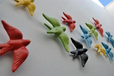 a white cake with different colored birds on it at Porta 20 in Loulé