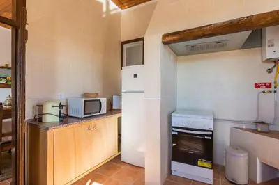 a small kitchen with a stove and a microwave at Solar da Rosa & Solar da Tirosa in Boliqueime