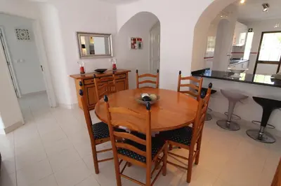 a kitchen and dining room with a wooden table and chairs at Apt T2 Praia São Rafael Hibiscus 18A - Albufeira, Algarve in Albufeira