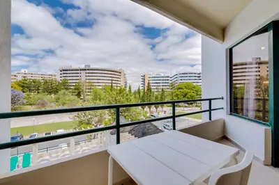 a balcony with a white table and a view of the city at Tália II - City Center - Vilamoura in Vilamoura