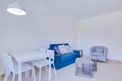 a living room with a blue couch and a table and chairs at Tália II - City Center - Vilamoura in Vilamoura
