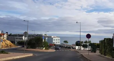 an empty street in a city with buildings and the ocean at Boas-Vindas in Albufeira