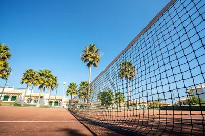 a tennis net on a tennis court with palm trees at Decor n' cozy place for families and friends in Guia