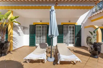 a patio with two chairs and an umbrella at Decor n' cozy place for families and friends in Guia