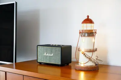 a radio and a lighthouse on a wooden table at Falésia Beach Villa by The Portuguese Butler in Olhos de Água
