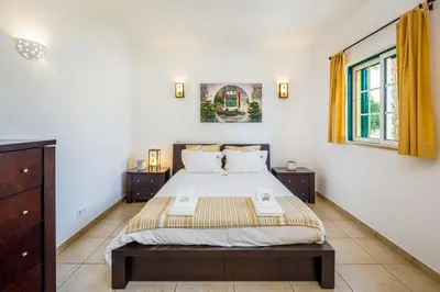 a bedroom with a large bed and two windows at Falésia Beach Villa by The Portuguese Butler in Olhos de Água