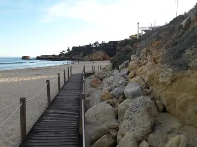 a wooden boardwalk leading to a beach with rocks at Quinta Cosy in Paderne