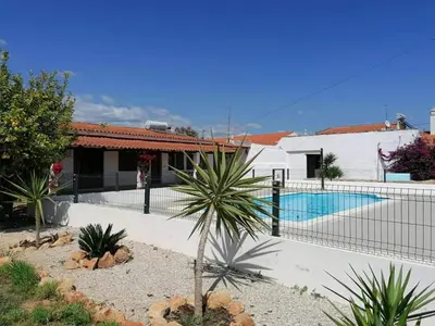 a house with a fence around a swimming pool at Quinta Cosy in Paderne