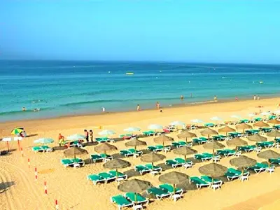 a beach filled with lots of green and white umbrellas at Luxury Apartment, 3 min Walk to Beach, Albufeira in Guia