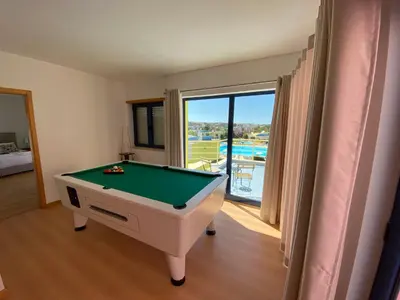 a pool table in a room with a view of a pool at Penthouse 160sqm wide Terraces Pool view & private Hot Tub & Parking in Albufeira