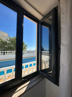 a bedroom with a white bed with a wooden headboard and a table at Vila Mar Central in Albufeira