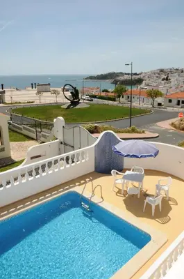 a swimming pool with chairs and a white fence at Vila Mar Central in Albufeira