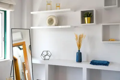 a white living room with white shelves and a vase at Downtown Pool House in Faro