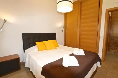 a bedroom with a bed with yellow pillows and white towels at Neptuno 97 - Clever Details in Vilamoura