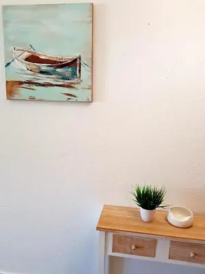 a painting of a boat on a wall next to a table at Neptuno 97 - Clever Details in Vilamoura