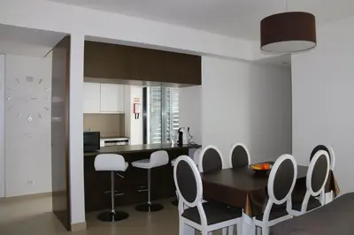 a kitchen with a wooden table and white chairs at Cavalo Preto Luxury Beach Resort in Quarteira